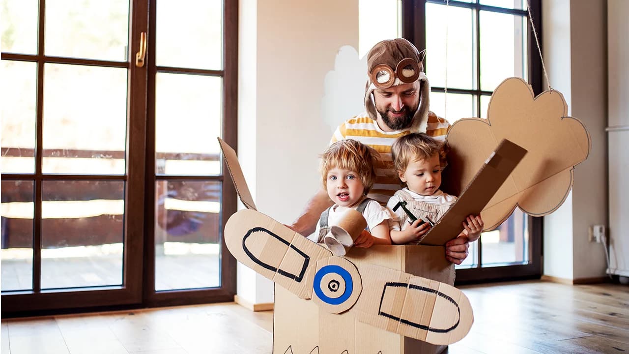 A parent and children building an imaginative cardboard airplane