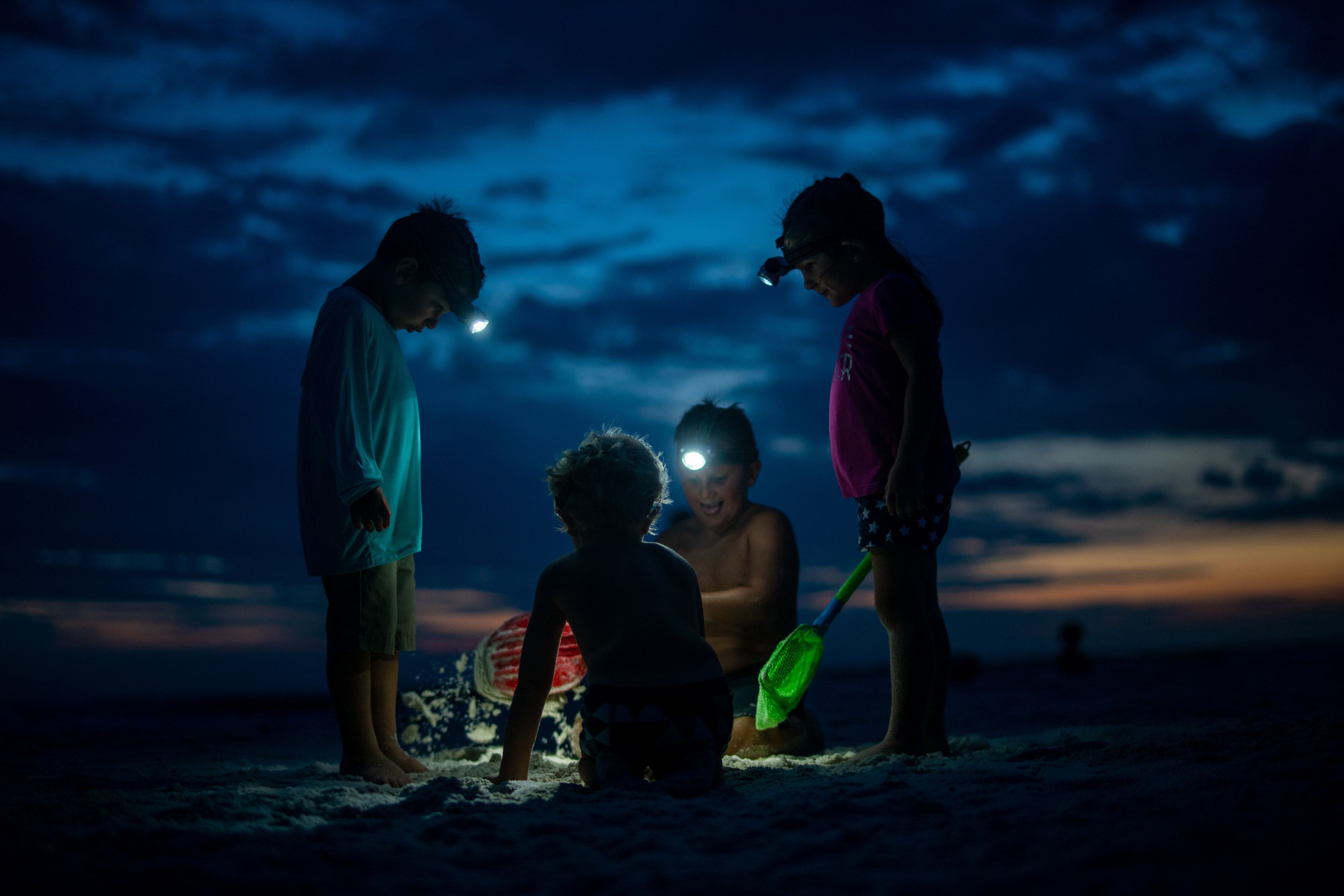 Children exploring a beach together after dark